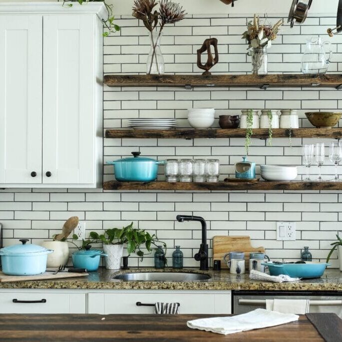 Rustic kitchen with shelves and plants.